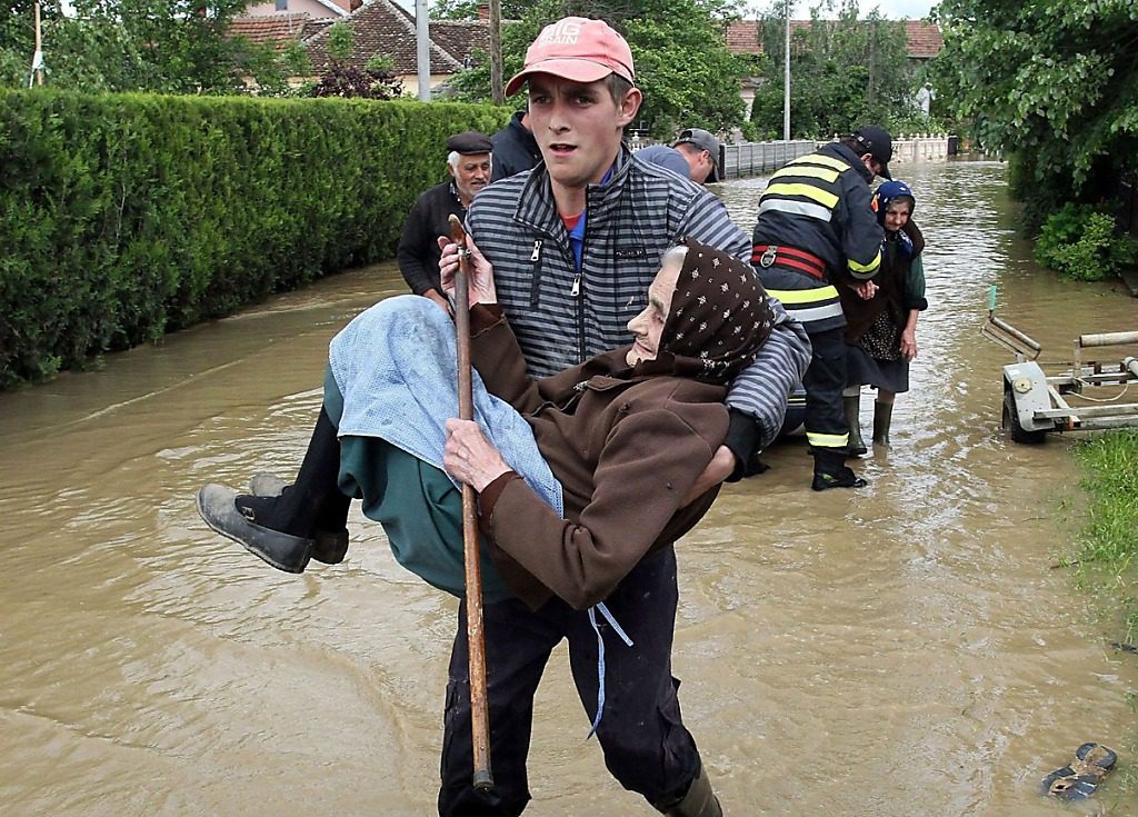 Young man carrying an old lady to safety